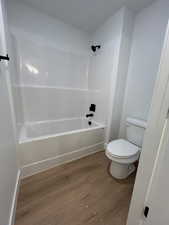 Bathroom with hardwood / wood-style floors,  shower combination, and toilet