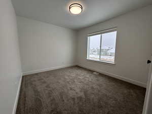 Spare room featuring dark colored carpet