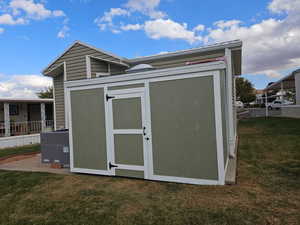 View of outdoor structure featuring a lawn and cooling unit