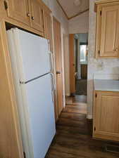 Kitchen featuring dark hardwood / wood-style flooring, white refrigerator, vaulted ceiling, and ornamental molding