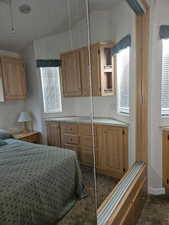 Bedroom with dark carpet, a closet, and multiple windows