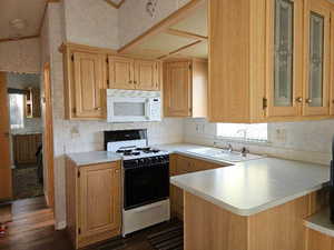 Kitchen featuring kitchen peninsula, white appliances, dark wood-type flooring, sink, and light brown cabinets