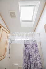 Bathroom with visible vents, shower / bath combination with curtain, and a skylight