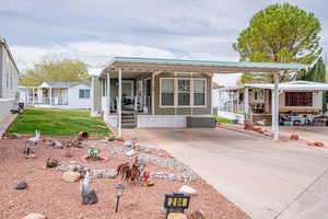 Manufactured / mobile home featuring a front lawn, covered porch, and concrete driveway