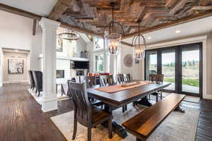 Dining space with ornate columns, french doors, dark hardwood / wood-style floors, and a notable chandelier