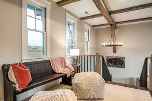 Living area with beam ceiling, a wealth of natural light, a notable chandelier, and coffered ceiling