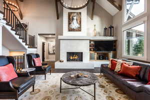 Living room featuring a high end fireplace, wood-type flooring, high vaulted ceiling, and beamed ceiling