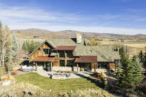 Back of property with a lawn, a mountain view, and a patio area