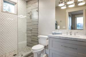 Bathroom featuring walk in shower, vanity, and toilet