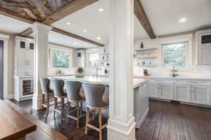 Kitchen featuring white cabinetry, wine cooler, dark hardwood / wood-style flooring, beamed ceiling, and backsplash