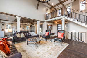 Living room featuring wood-type flooring, a towering ceiling, coffered ceiling, and beam ceiling