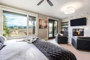 Carpeted bedroom with access to exterior, ceiling fan, and a multi sided fireplace