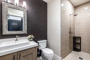 Bathroom featuring vanity, toilet, tile walls, and walk in shower