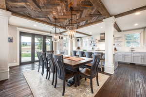 Dining area featuring a notable chandelier, dark hardwood / wood-style floors, and decorative columns