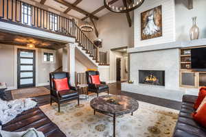 Living room with a towering ceiling, coffered ceiling, beam ceiling, a premium fireplace, and hardwood / wood-style floors