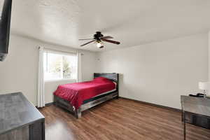 Bedroom featuring ceiling fan, dark hardwood / wood-style flooring, and a textured ceiling