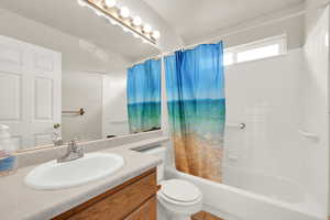 Full bathroom featuring shower / bath combination with curtain, vanity, and toilet