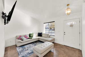 Living room with tile patterned floors and vaulted ceiling