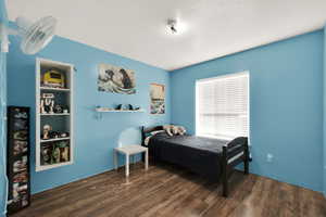 Bedroom with a textured ceiling and dark wood-type flooring