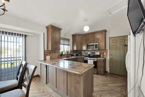 Kitchen with sink, tasteful backsplash, kitchen peninsula, light hardwood / wood-style floors, and appliances with stainless steel finishes