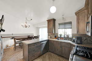 Kitchen featuring pendant lighting, backsplash, sink, kitchen peninsula, and stainless steel appliances