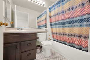 Full bathroom with tile patterned flooring, vanity, toilet, and shower / bathtub combination with curtain