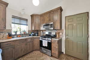 Kitchen featuring decorative backsplash, sink, and appliances with stainless steel finishes