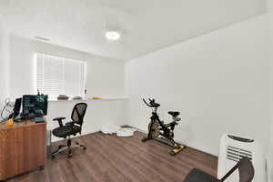 Home office with hardwood / wood-style floors and a textured ceiling