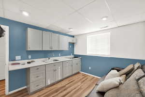 Kitchen featuring gray cabinetry, sink, stovetop, and light hardwood / wood-style flooring