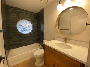 Full bathroom with hardwood / wood-style floors, vanity, toilet, and tiled shower / bath combo