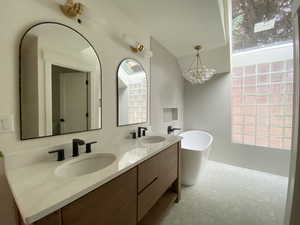 Bathroom with vanity, an inviting chandelier, a bathtub, and a healthy amount of sunlight