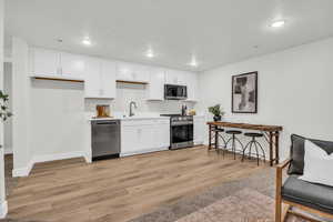 Kitchen featuring light hardwood / wood-style floors, white cabinetry, sink, and appliances with stainless steel finishes