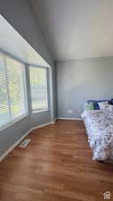 Bedroom with hardwood / wood-style floors and vaulted ceiling