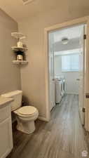 Bathroom with separate washer and dryer, toilet, and hardwood / wood-style flooring