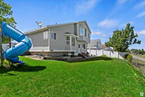 Rear view of property featuring a lawn and a playground