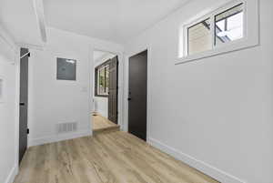 Empty room with light hardwood / wood-style floors and electric panel