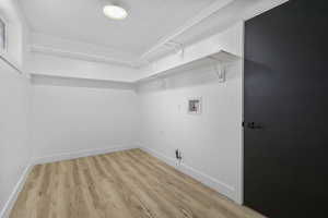 Clothes washing area featuring washer hookup and light hardwood / wood-style flooring