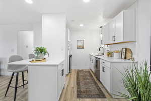 Kitchen featuring light wood-type flooring, white cabinetry, and a breakfast bar area