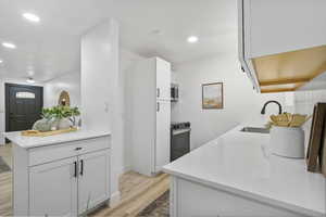 Kitchen with white cabinets, appliances with stainless steel finishes, light wood-type flooring, and sink