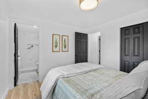 Bedroom with light wood-type flooring and ensuite bathroom