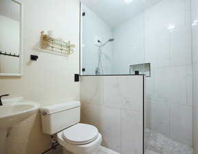 Bathroom featuring a textured ceiling, toilet, and tiled shower