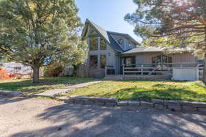 View of front of property featuring a wooden deck and a front lawn