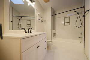 Full bathroom with toilet, a skylight, tiled shower / bath, and vanity