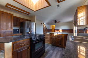 Kitchen featuring a center island, sink, dark wood-type flooring, black range with electric cooktop, and stainless steel fridge