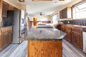 Kitchen with stainless steel fridge with ice dispenser, ceiling fan, a kitchen island, light hardwood / wood-style flooring, and sink