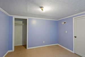 Unfurnished bedroom with crown molding, a textured ceiling, and a closet