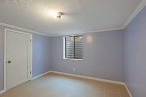 Tiled spare room with crown molding and a textured ceiling