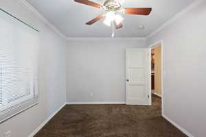 Spare room with dark carpet, ceiling fan, and ornamental molding