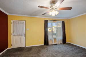 Unfurnished room featuring ceiling fan, dark carpet, crown molding, and a textured ceiling