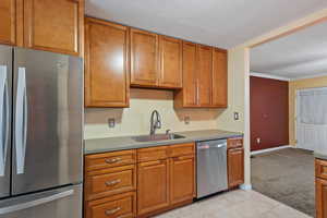 Kitchen with sink, stainless steel appliances, a textured ceiling, light tile patterned floors, and ornamental molding